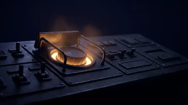 One large control under a raised guard on a dark console, lit from beneath in amber while every other control stays unlit.